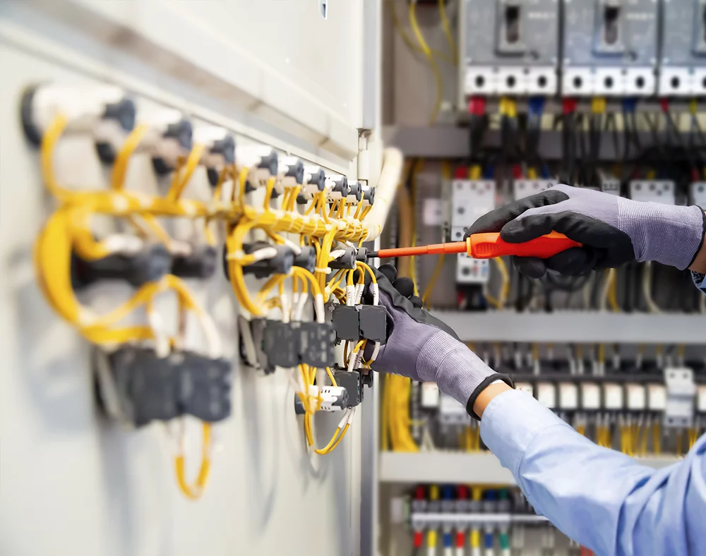 Electricians work to connect electric wires in Control cabinet